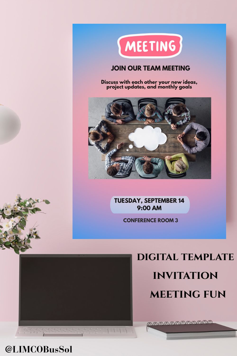 A digital template meeting invitation poster displayed on a pink wall above a desk with a laptop and notebook. The poster features a blue-to-pink gradient background with a central photo of people around a table and text reading 'MEETING' and 'JOIN OUR TEAM MEETING'.